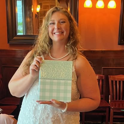 Bride holding a gift-wrapped wedding cookbook